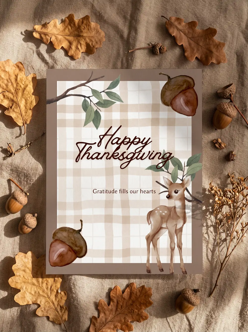 The printed Acorn & Fawn thank you card on rumpled beige linen, among fallen oak leaves, acorns and a sprig of dried flowers