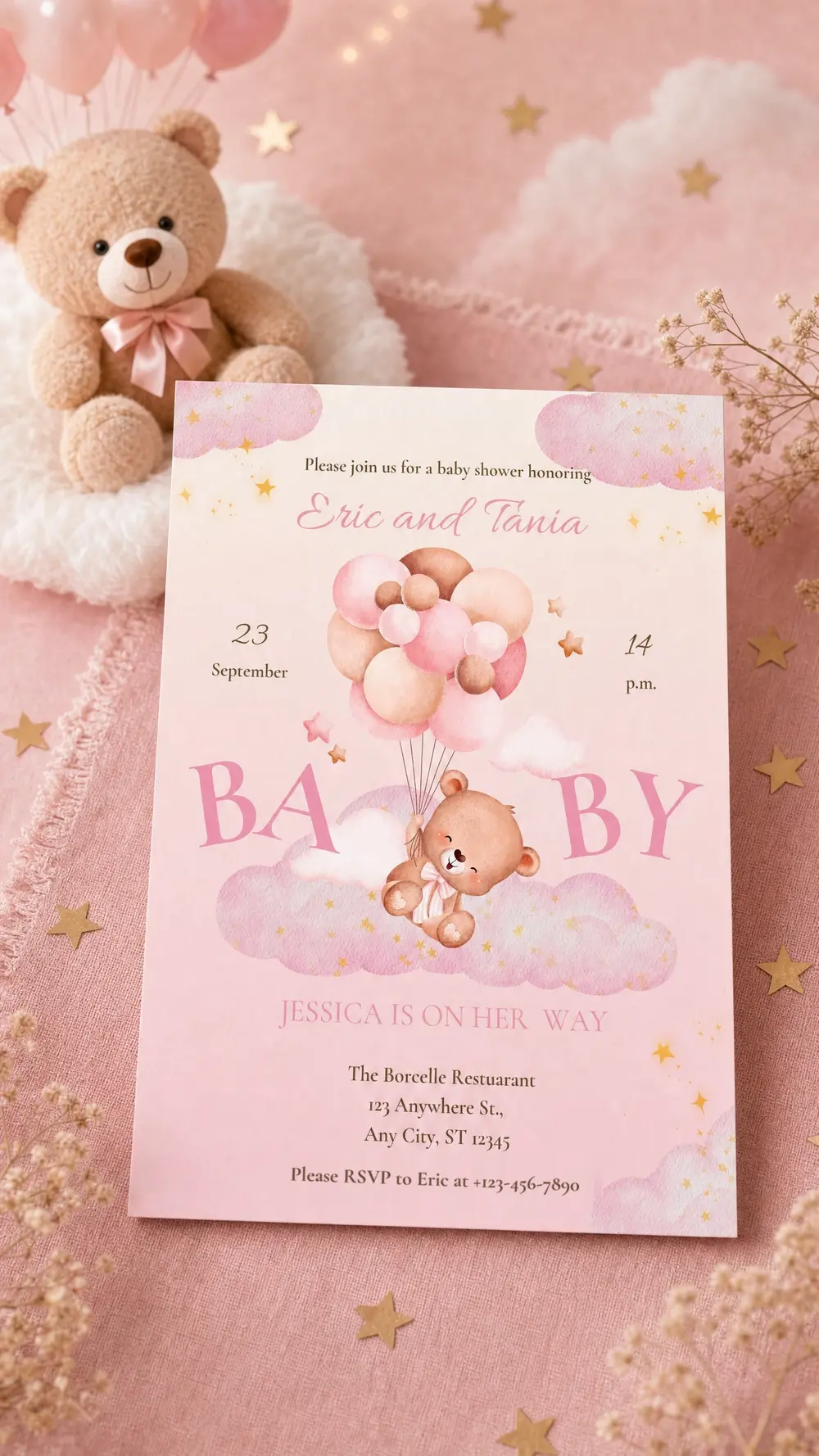 The printed Up and Away invitation standing on pink linen beside a plush teddy bear, pink balloons, gold stars and sprigs of baby's breath